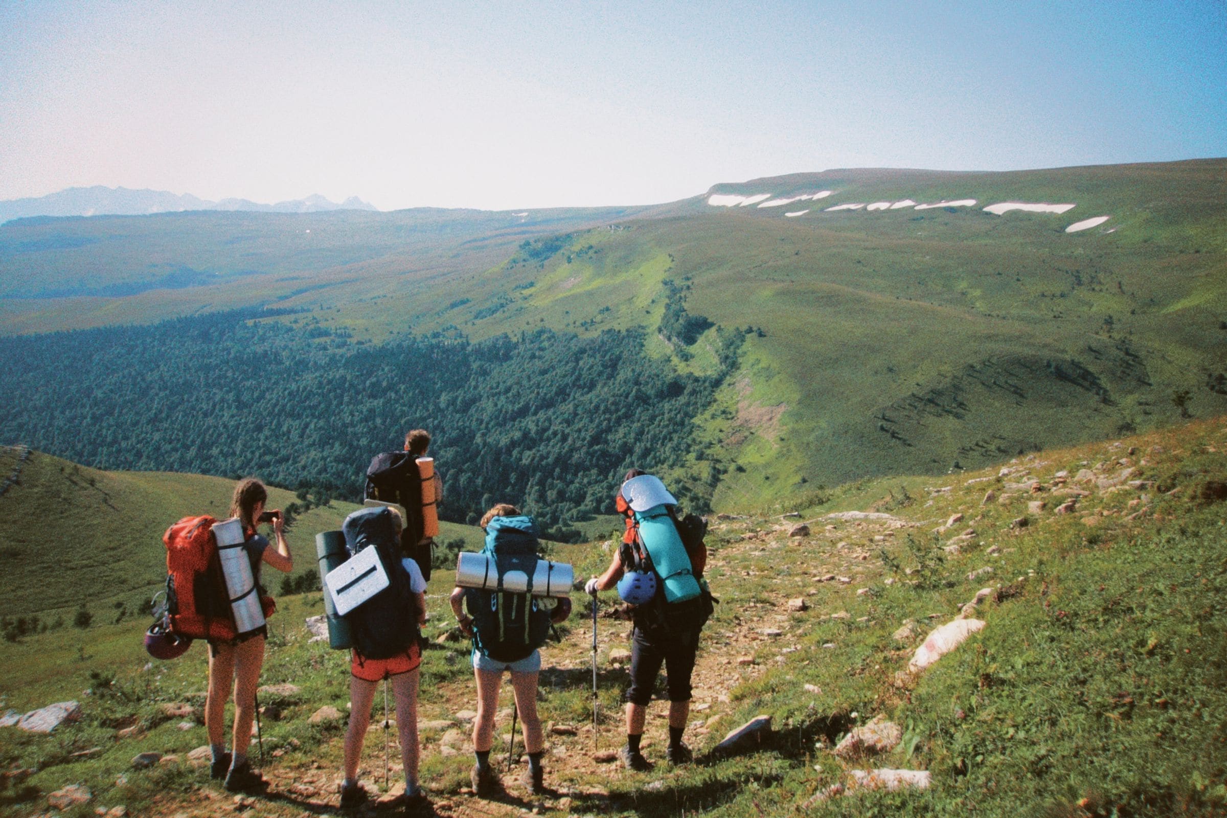 Friends with backpacks hiking a green mountain trail
