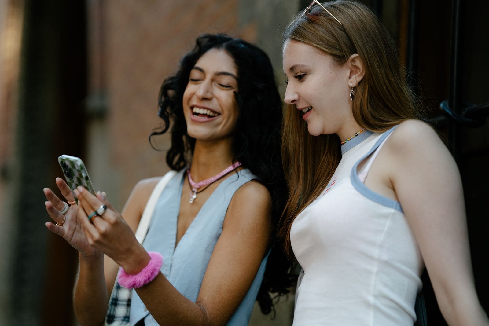Two women smiling together while looking at a phone