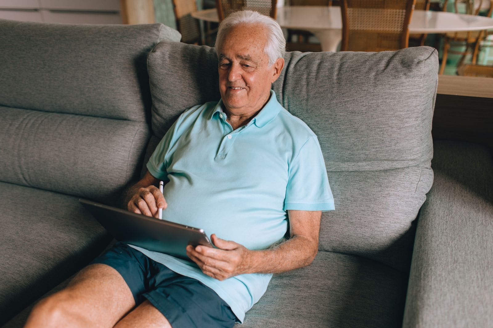 Man smiling while using a tablet on his sofa