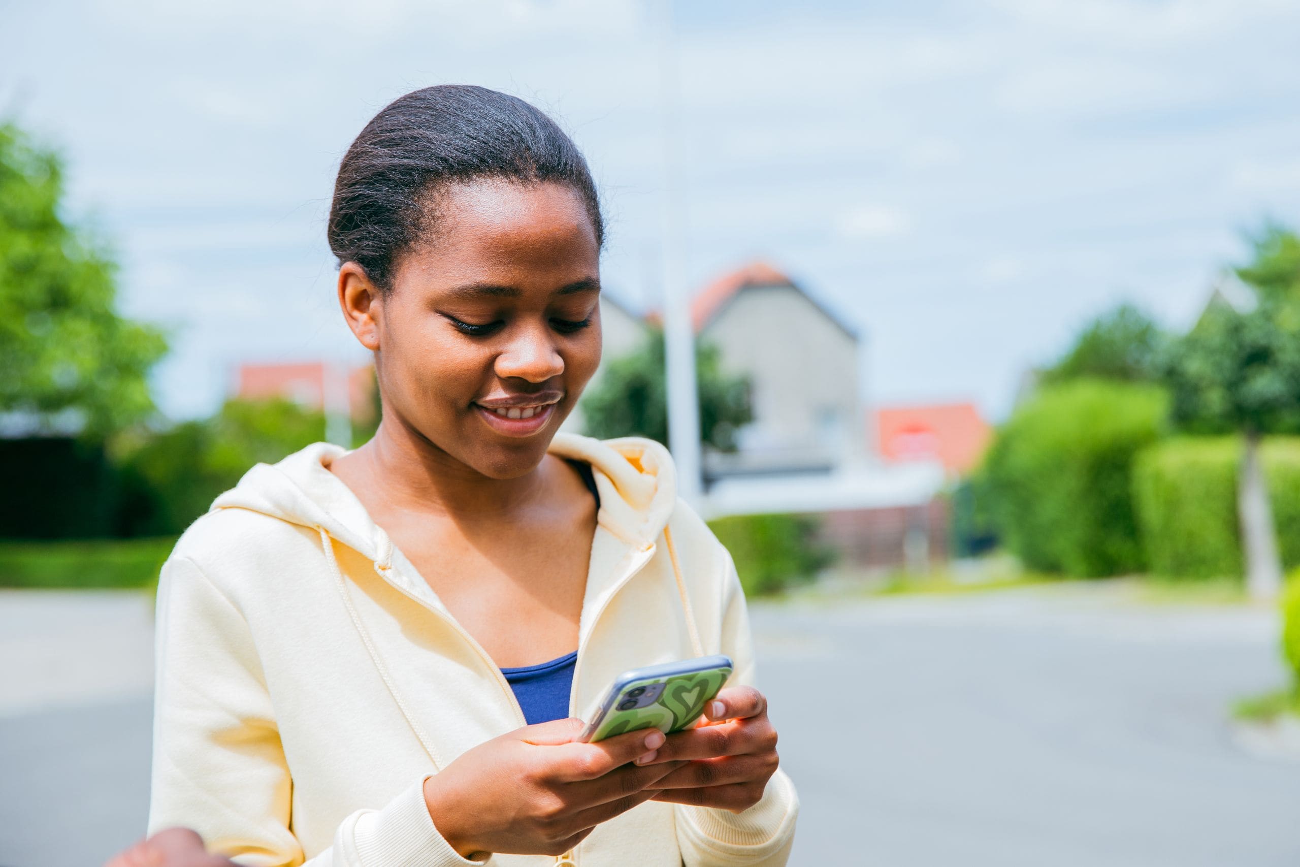 Woman smiling while using a phone outside