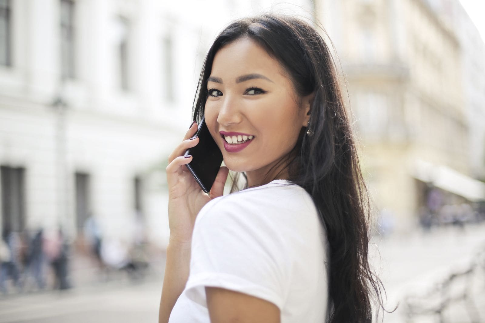 Woman smiling while using her phone on a city street