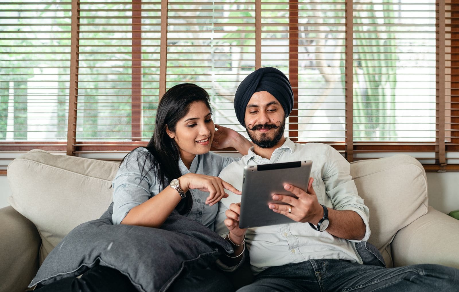Two people sharing a tablet on a sofa
