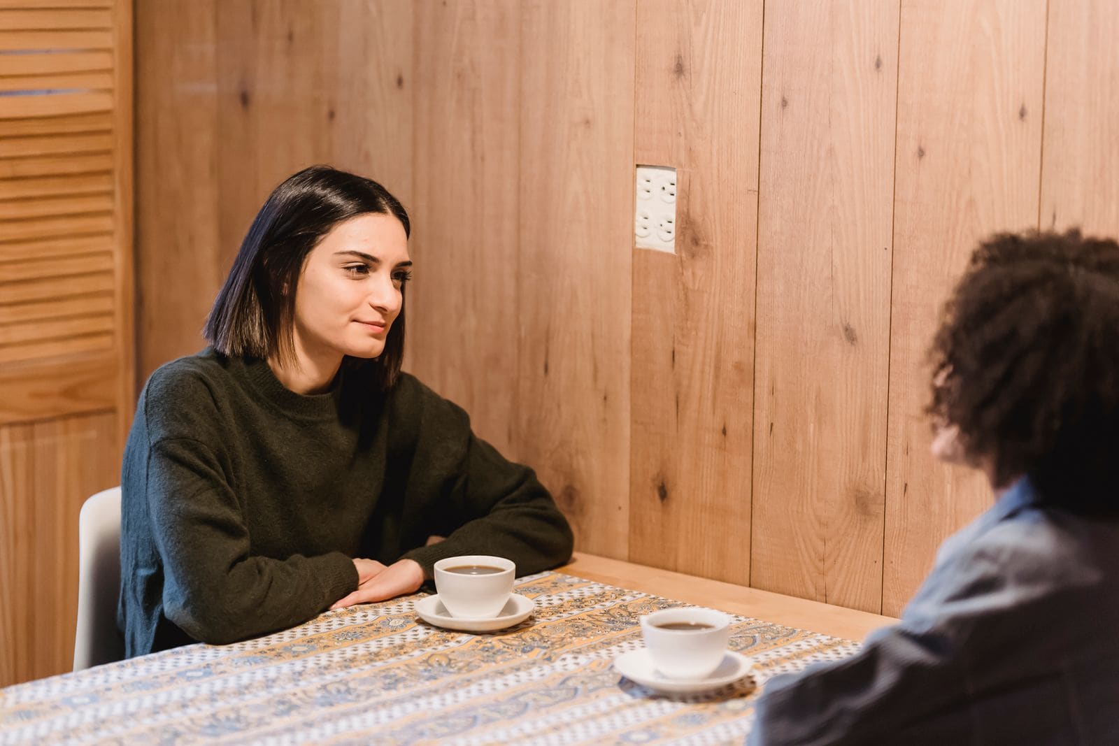 Two friends talking across a café table