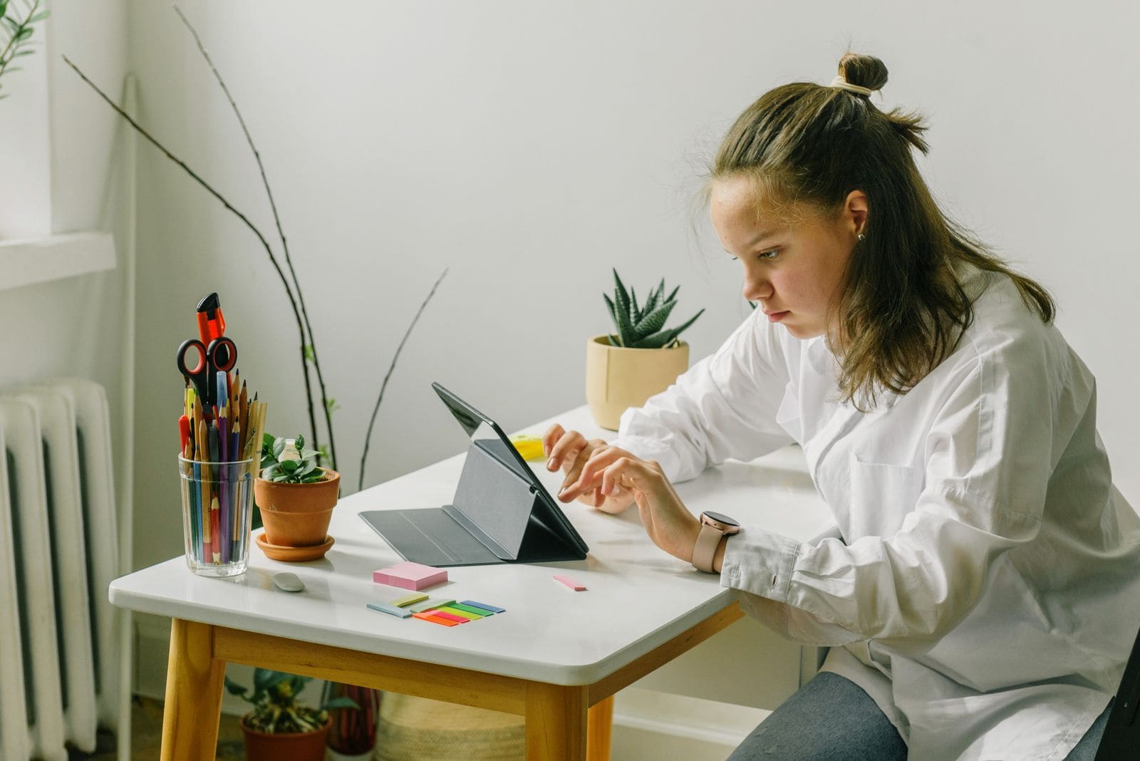 Woman using a tablet at a desk with plants