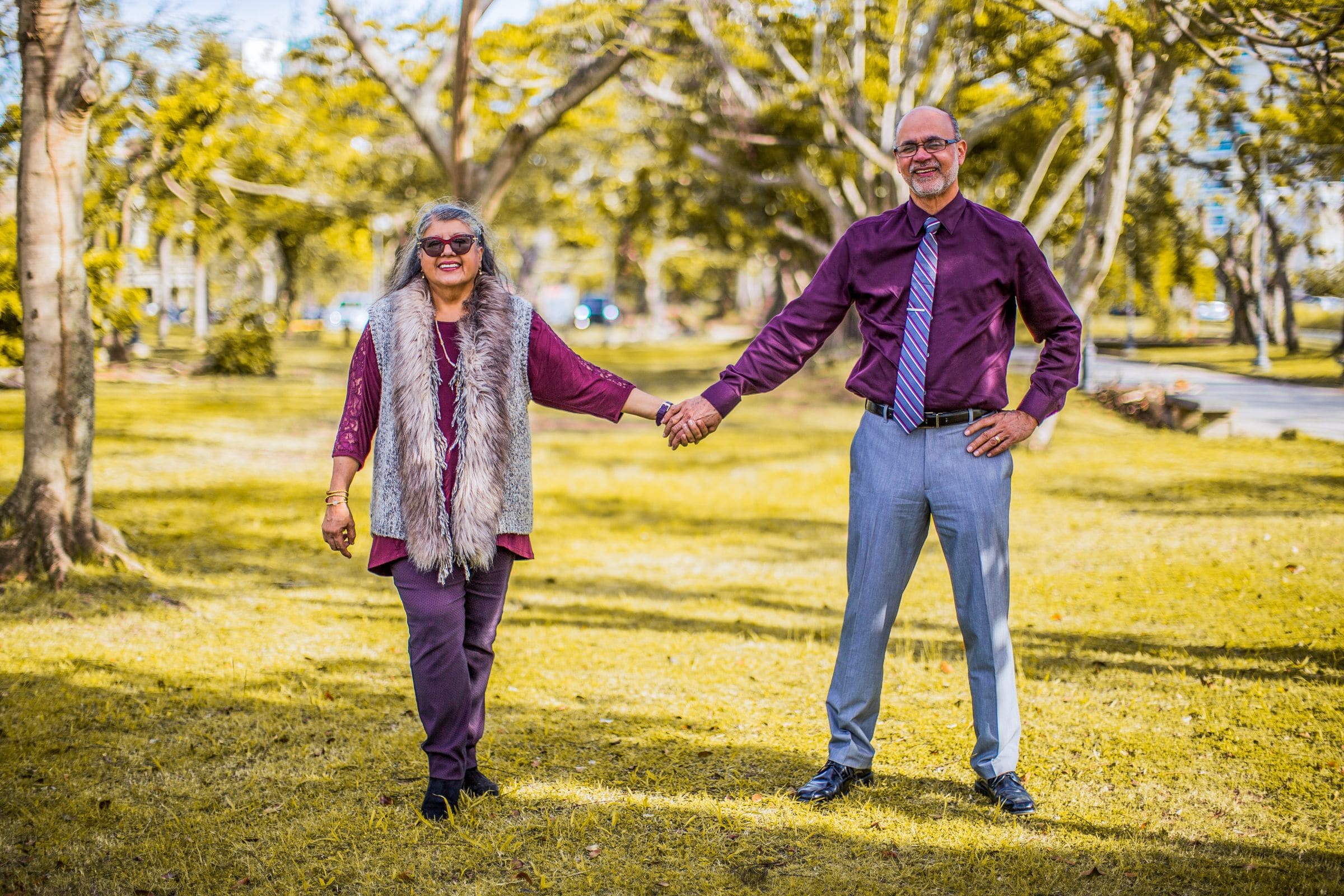 Mature couple smiling and holding hands in a green park