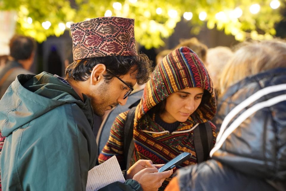 Two people checking a phone together at an outdoor event